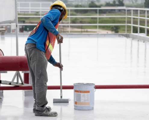 Roof restoration worker applying tpo coating