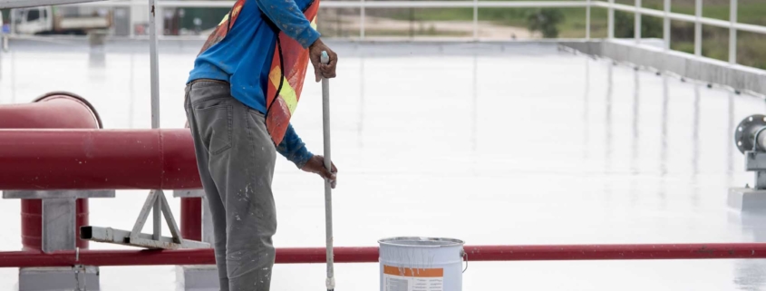 Roof restoration worker applying tpo coating